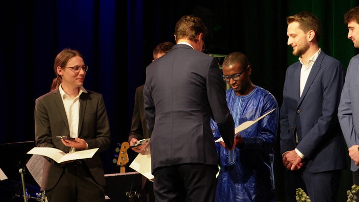 NRW-Ministerpräsident Hendrik Wüst übergibt Mamadou Tanou Diallo die Rettungsmedaille.