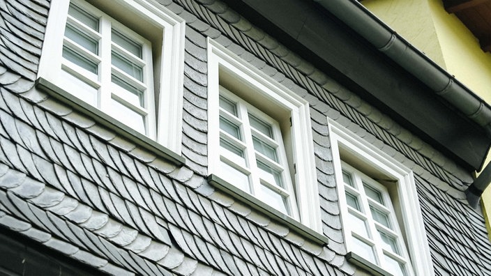 Foto von einem verschieferten Haus mit mehreren Fenstern, die auf kipp sind
