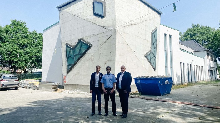Volkan Eren steht mit Vertretern der bosnischen Gemeinde in Essen vor einer Moschee.