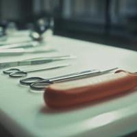 Auf einem weißen Tisch liegen mehrere Metallinstrumente, die zur Obduktion verwendelt werden, wie ein Messer oder kleine Scheren und Pinzetten.