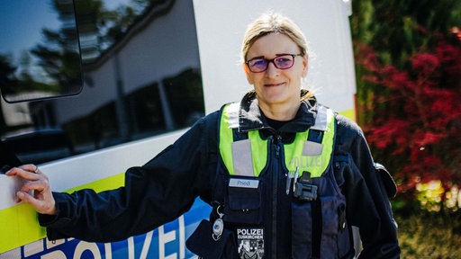 Frauke Prieß stützt sich an einem Dienstfahrzeug ab. Sie lächelt.