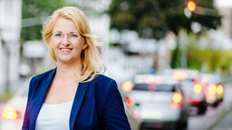 Daniela Rechberger im Portrait, dahinter eine Szenerie aus dem Straßenverkehr.