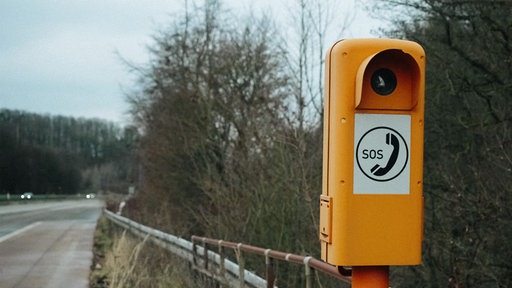 Eine orangene SOS-Säule auf der Autobahn.