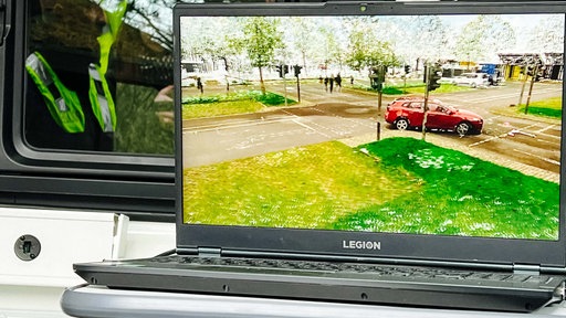 Auf einem Laptop sind eine Kreuzung und ein rotes Auto zu sehen.