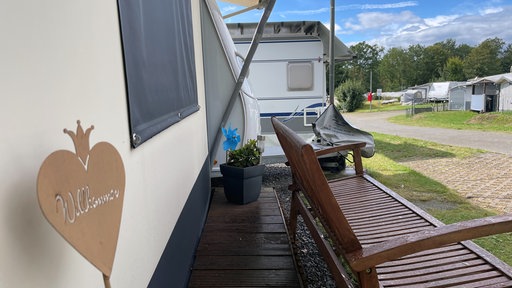 Ein Bild von einem Wohnmobil mit einer Bank auf dem Campingplatz Vier Jahreszeiten. 