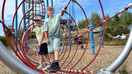 Zwei Jungen sind auf einem Spielplatz und lächeln in die Kamera 
