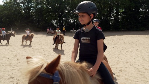 Ein Kind reitet auf einem Pony.