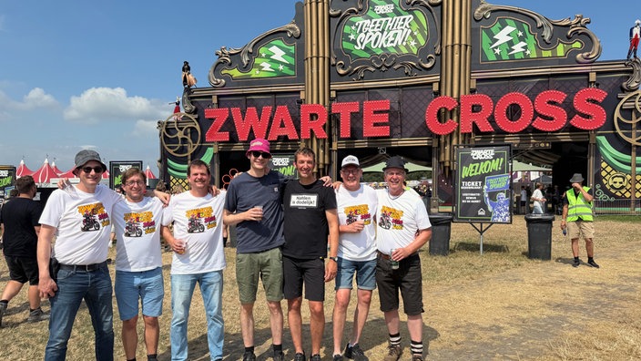 Eine Gruppe posiert für ein Foto vor dem Eingangstor des Festivals.