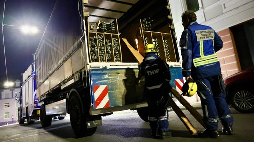Zwei Einsatzkräfte mit Ausrüstung vor einem Lkw vor einem Haus in Wuppertal