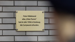 Gedenktafel in Duisburg in Marxloh, Aufschrift: Peter Hildebrand alias „Peter Pomm“ hat im Jahr 1936 in Duisburg die Currywurst erfunden.