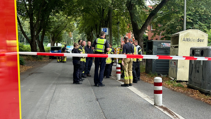 Das Bild zeigt die Polizei hinter Absperrband auf einer Straße