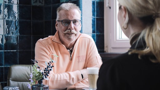 Günter Breitenberger in einem Cafe an einem Tisch sitzend.