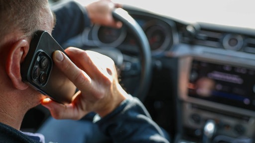 Ein Mann telefoniert in seinem Auto mit einem Smartphone