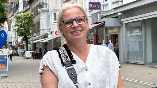 Heike Wortmann lächelt in einer Fußgängerzone in die Kamera 