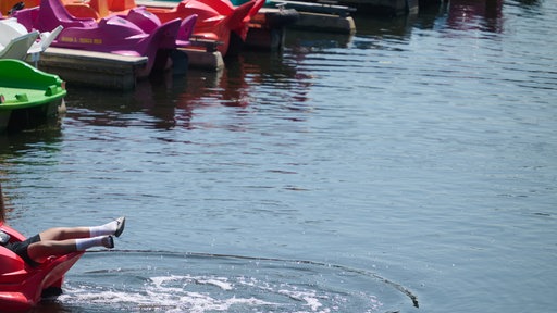 Ein Mann liegt auf einem Tretboot am Kemnader See an einem Steg und lässt die Beine baumeln