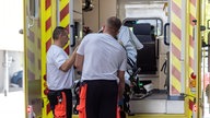 Rettungssanitäter heben eine Patientin aus dem Rettungswagen