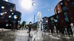 Ein Kind läuft in Duisburg durch einen Springbrunnen