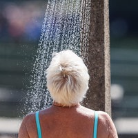 Eine Frau steht zur Abkühlung im Freibad Wolfssee unter der Dusche