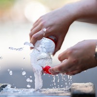 Ein Mann füllt an einem Trinkwasserbrunnen eine Flasche auf.