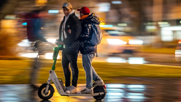 Jugendliche fahren zu zweit auf einem E-Scooter