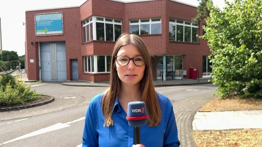 Eine Reporterin steht mit Mikrofon vor der JVA Siegburg.