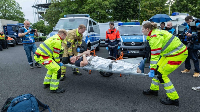  Person wird von Einsatzkräften auf einer Trage getragen