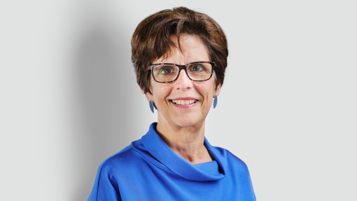 Eine Frau mit dunkleren Haaren und einer Brille