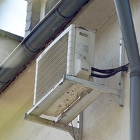 Eine Klimaanlage hängt an der Hauswand eines Mehrfamilienhauses