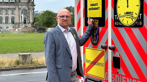 Sören Link neben einem Rettungswagen mit einem Schild: "Einsatz gefährdet?"
