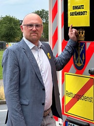 Sören Link neben einem Rettungswagen mit einem Schild: "Einsatz gefährdet?"