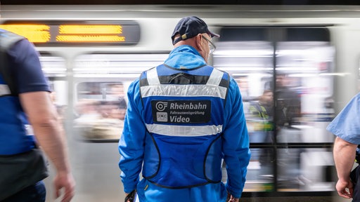 Ein Rheinbahn-Mitarbeiter steht vor einer fahrenden U-Bahn