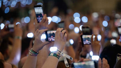 Zuschauer filmen während des Konzerts von Sängerin Taylor Swift in der Veltins-Arena mit ihren Smartphones
