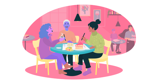 Drei Freund:innen sitzen an einem Tisch im Cafe und bemalen ein Stück Kuchen. 