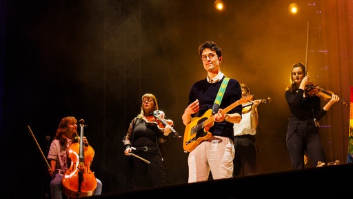 Christopher Annen, Gitarrist von AnnenMayKantereit, steht mit Streichern beim Southside-Festival auf der Bühne. (2025)