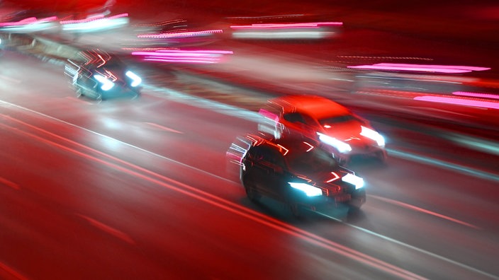 Auf dem Bild sind schnell fahrende Autos bei Nacht zu sehen