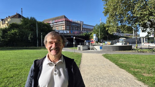 Ein Mannes auf der Wiese des Bergbaumseums in Bochum. Im Hintergrund der Abgang zur U-Bahn-Haltestelle.