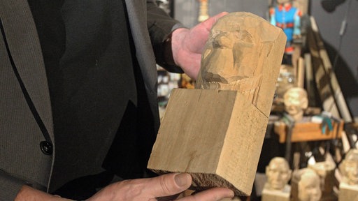 Eine Hand hält ein bearbeitetes Stück Lindenholz