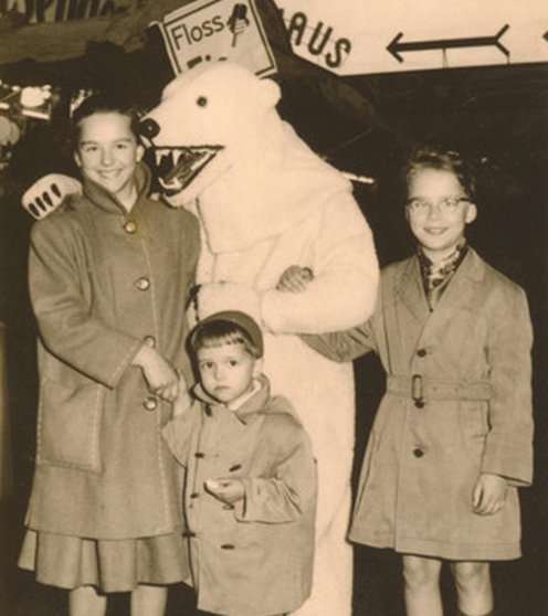 Drei Kinder stehen neben und vor einem Eisbär.