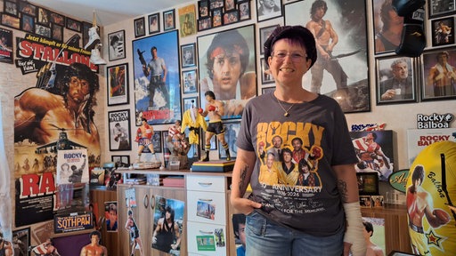 Eine Frau mit einem Rocky-T-Shirt und im zahlreichen Rocky-Plakaten im Hintergrund.