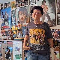 Eine Frau mit einem Rocky-T-Shirt und im zahlreichen Rocky-Plakaten im Hintergrund.