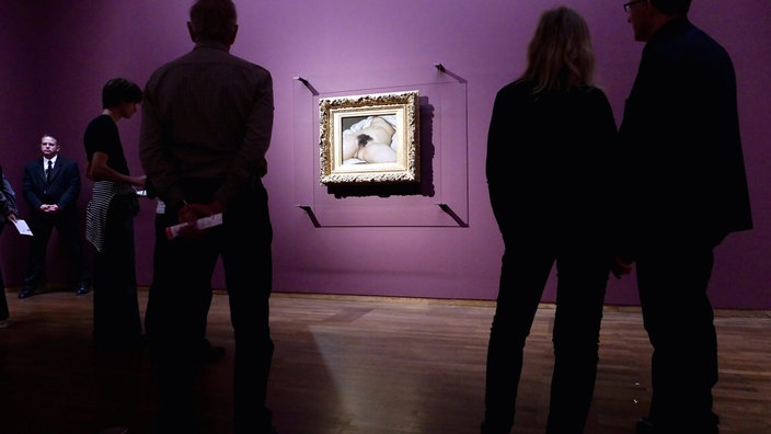 Auf dem Bild ist zu sehen, wie verschiedene Museumsbesucher das Gemälde "Der Ursprung der Welt" anschauen 