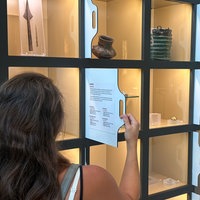 Eine Museumsbesucherin betrachtet in einer Vitrine Ausstellungsstücke.