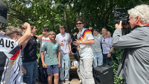 Mann mit Saxophon lacht während Schüler um ihn herum tanzen