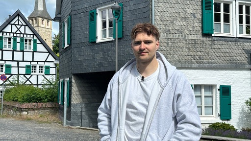 Mann steht vor einem alten bergischen Fachwerkhaus mit Fensterläden