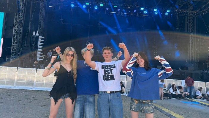 Jugendliche schwingen gut gelaunt ihre Fäuste hoch vor einer der Bühnen beim Juicy Beats Musik Festival.