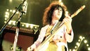 Marc Bolan steht in den 70er Jahren bei einem Auftritt auf der Bühne. Er spielt mit geschlossenen Augen E-Gitarre