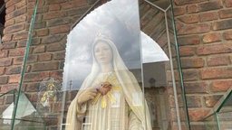 Marienfigur hinter Glas vor der Kirche in Sievernich
