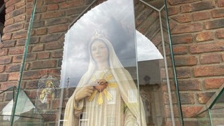 Marienfigur hinter Glas vor der Kirche in Sievernich