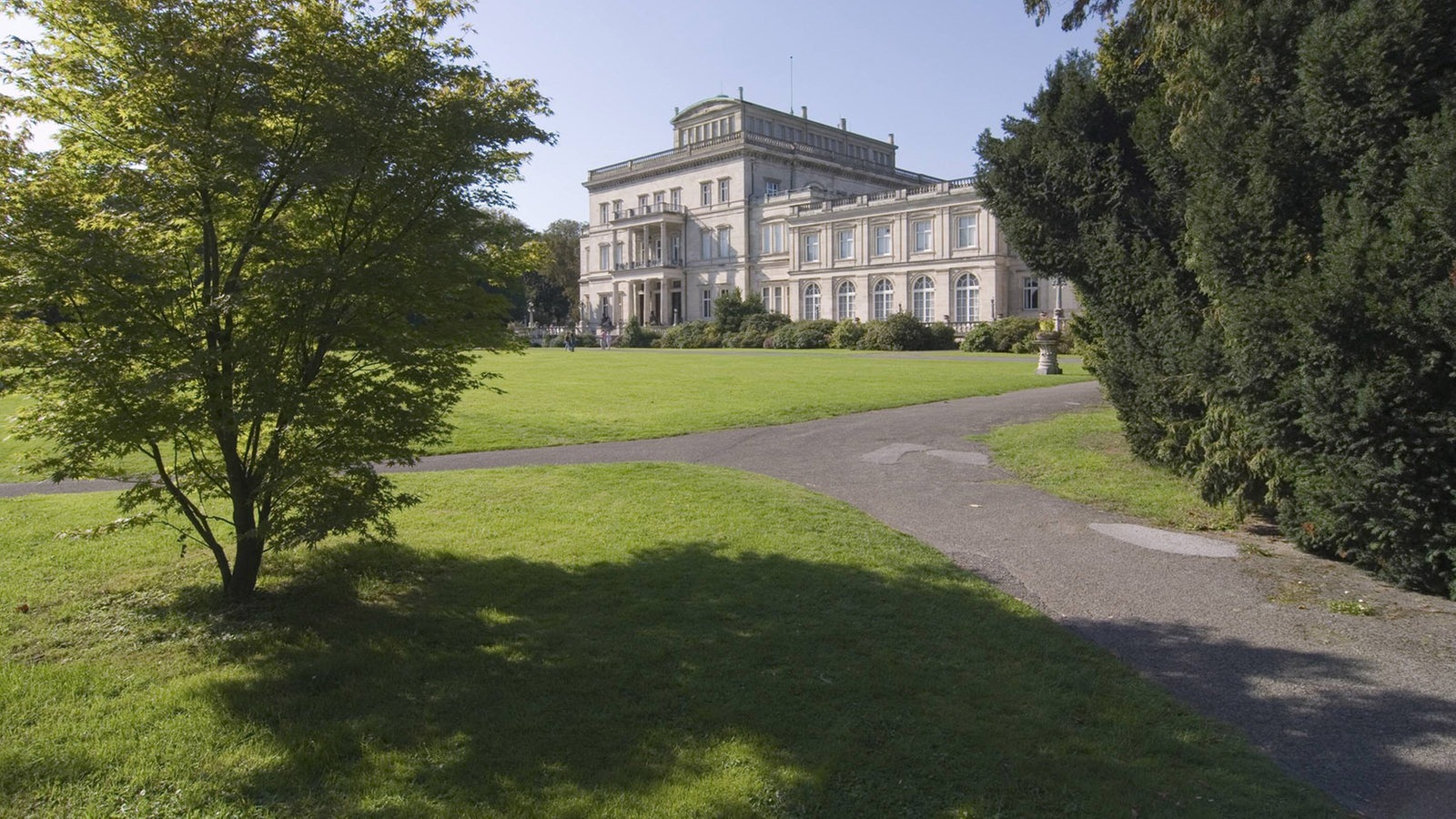 Weg zwischen Büschen zu einem Haus im Hintergrund