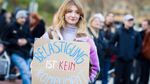 Eine Frau mit einem Schild "Belästigung ist kein Kompliment"